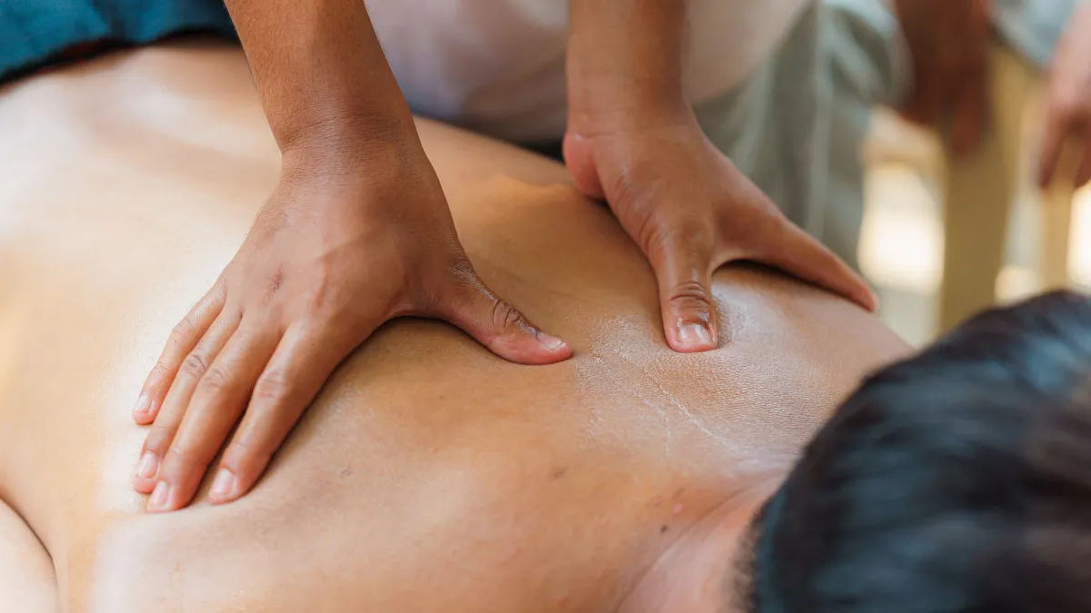 Terapeut aplicând tehnici de masaj deep tissue pe spatele unui client într-un cabinet de wellness